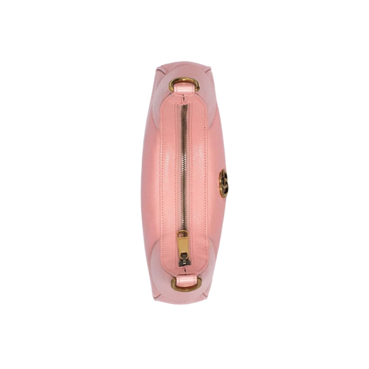 Pink handbag with gold zipper and clasp on a light purple background