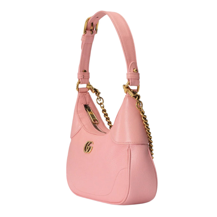 Pink handbag with gold chain detail on a light purple background