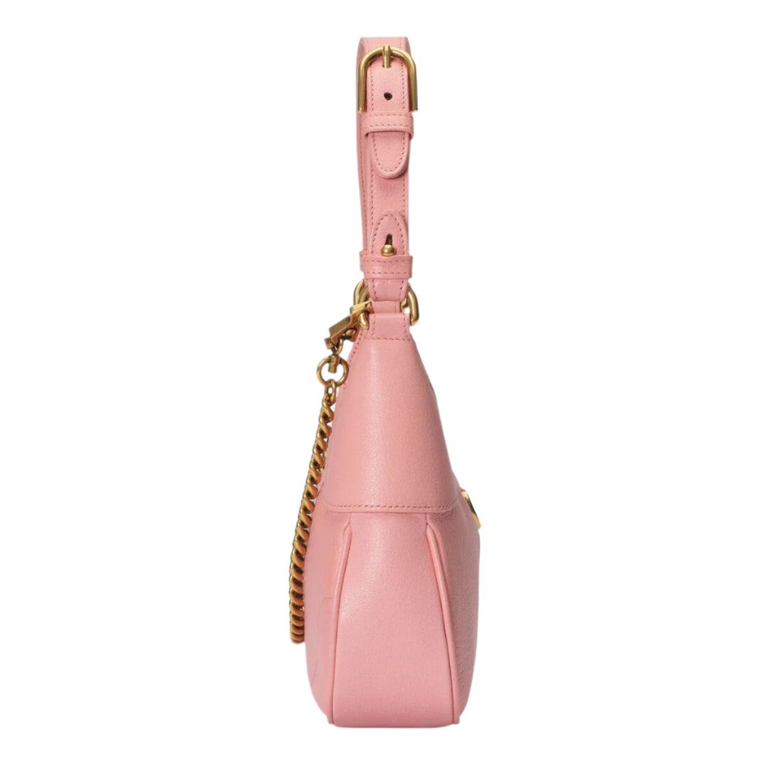 Pink handbag with gold chain and strap on a light purple background