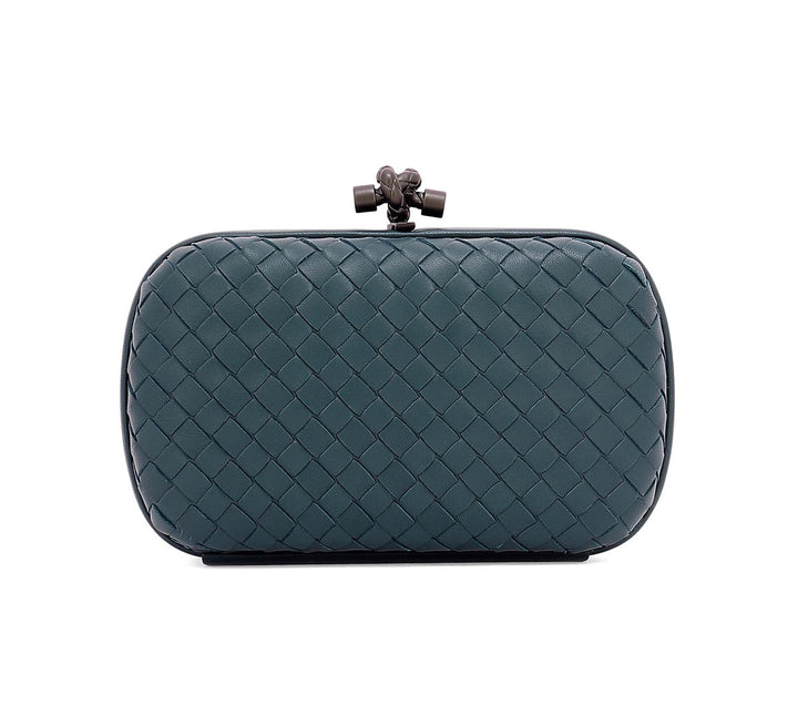 A woven leather clutch bag in a dark teal blue-green color, featuring a diamond-weave pattern and a dark metal clasp at the top, shown against a plain white background.