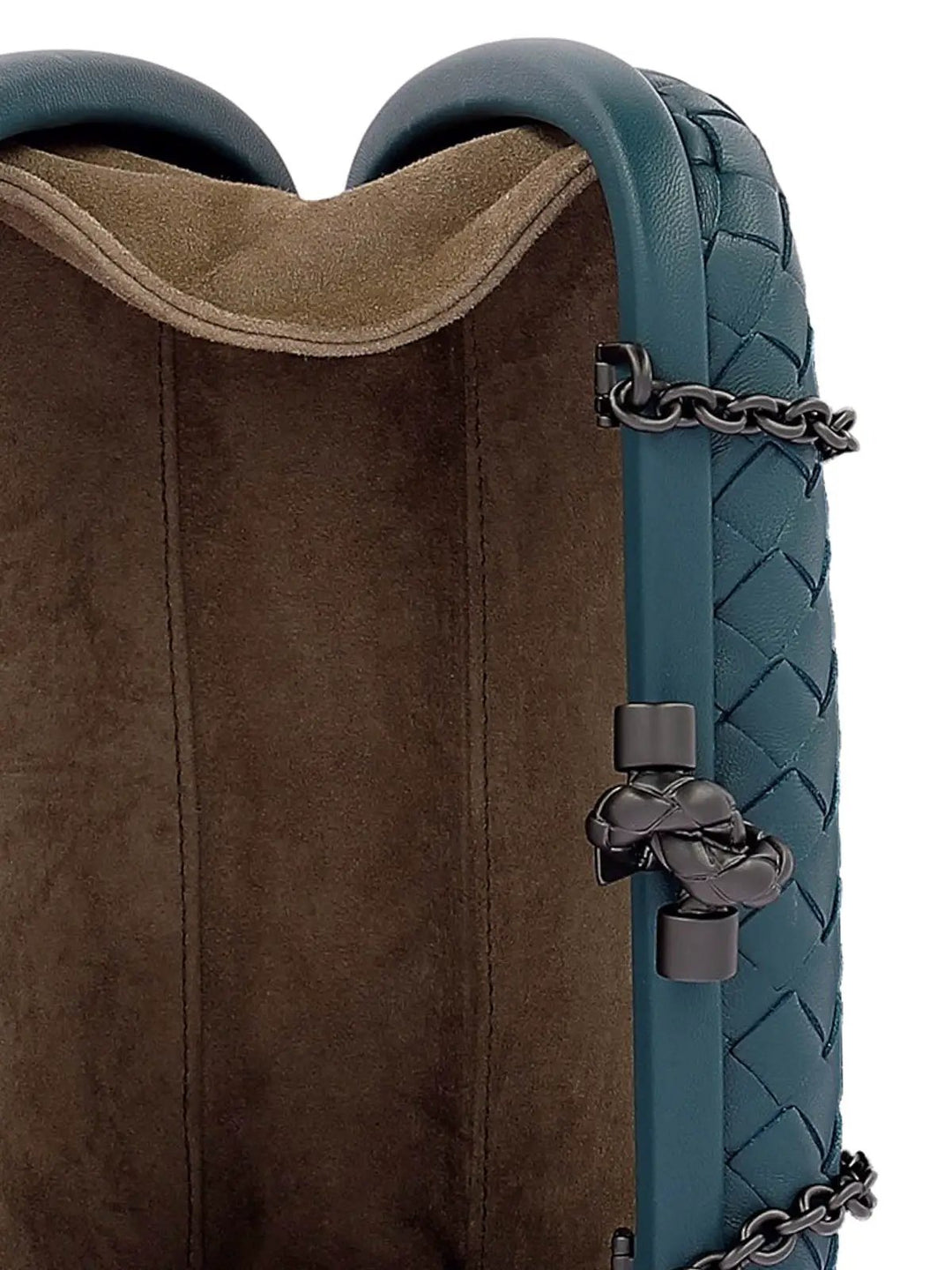 Close-up of a luxury handbag showing the dark teal woven leather strap, dark gunmetal chain accents, and a brown suede-textured interior lining.
