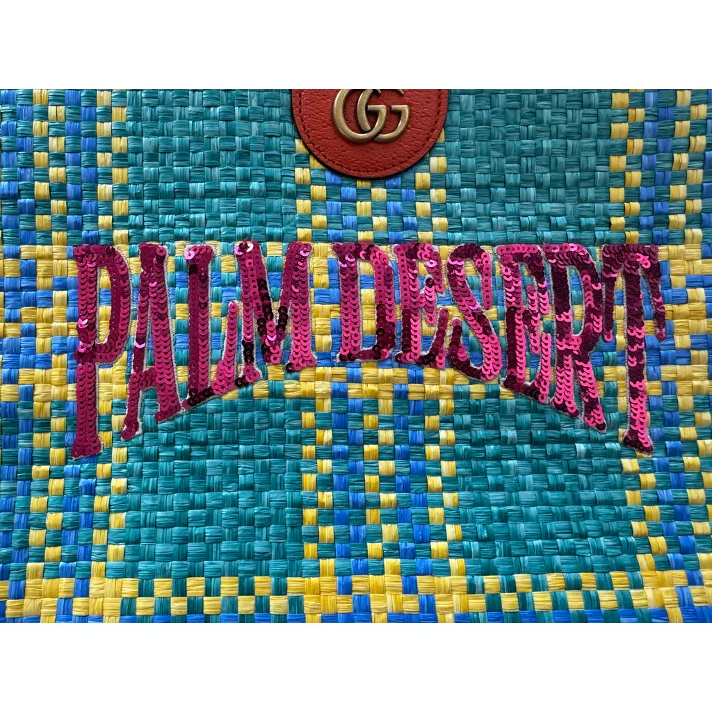 Text 'PALM DESERT' on a woven fabric background with Gucci logo.