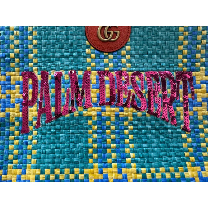 Text 'PALM DESERT' on a woven fabric background with Gucci logo.