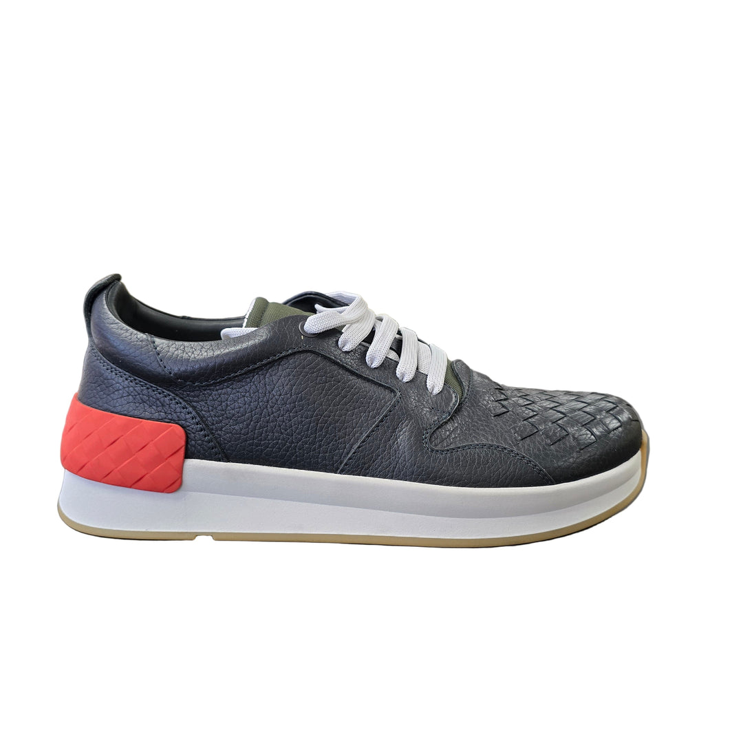 Gray sneaker with a red sole on a gray surface
