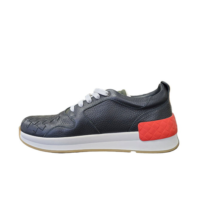 Gray sneaker with red accents on a black surface, blurred background