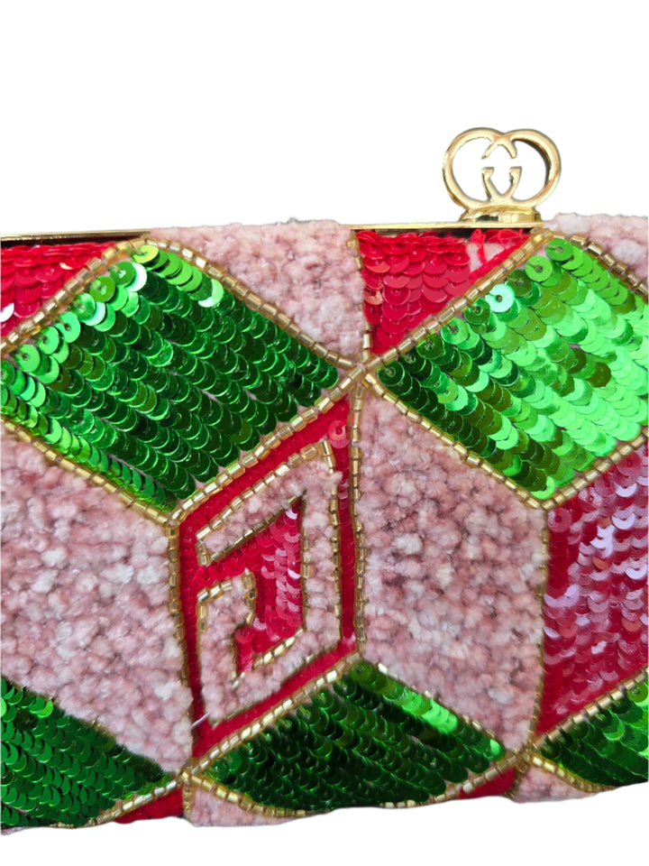 Close-up of a decorative item with green and red sequins on a pink textured background.